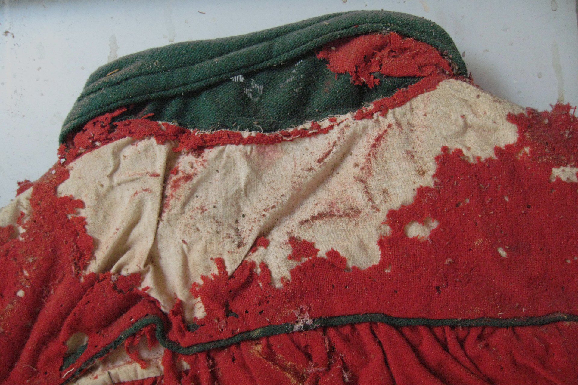 Il tessuto di lana rosso della giubba garibaldina è gravemente danneggiato dall'infestazione di tarme. Tomedi Textilrestaurierung