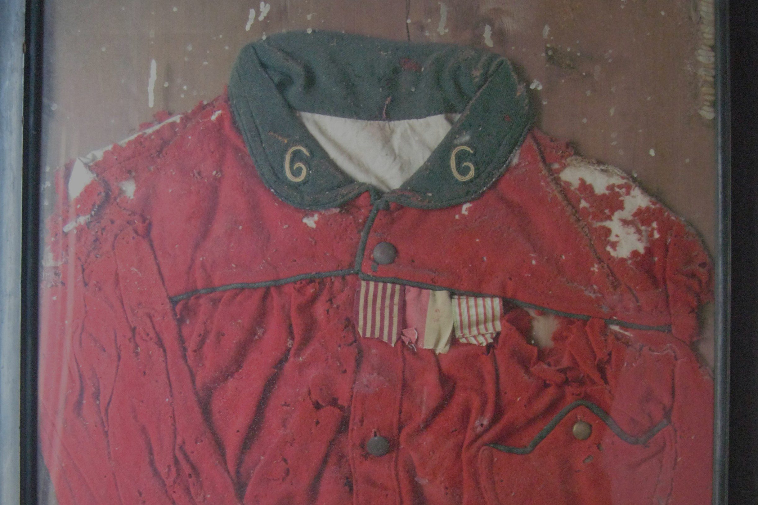 Prima del restauro la giubba garibaldina è conservata in una cornice sotto vetro. Tomedi Textilrestaurierung