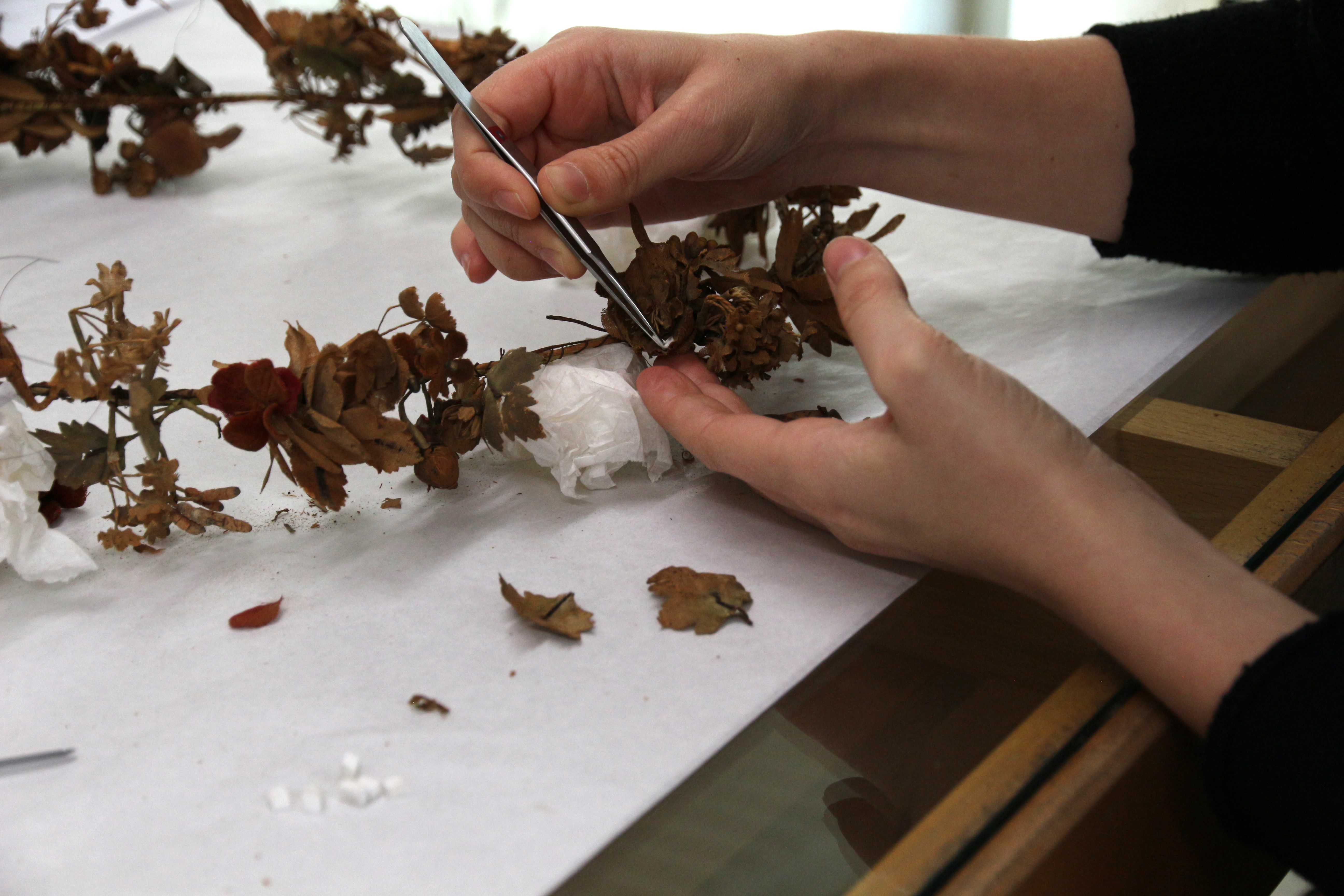 The fabric petals are cleaned using tweezers and small sponges. Tomedi Textilrestaurierung