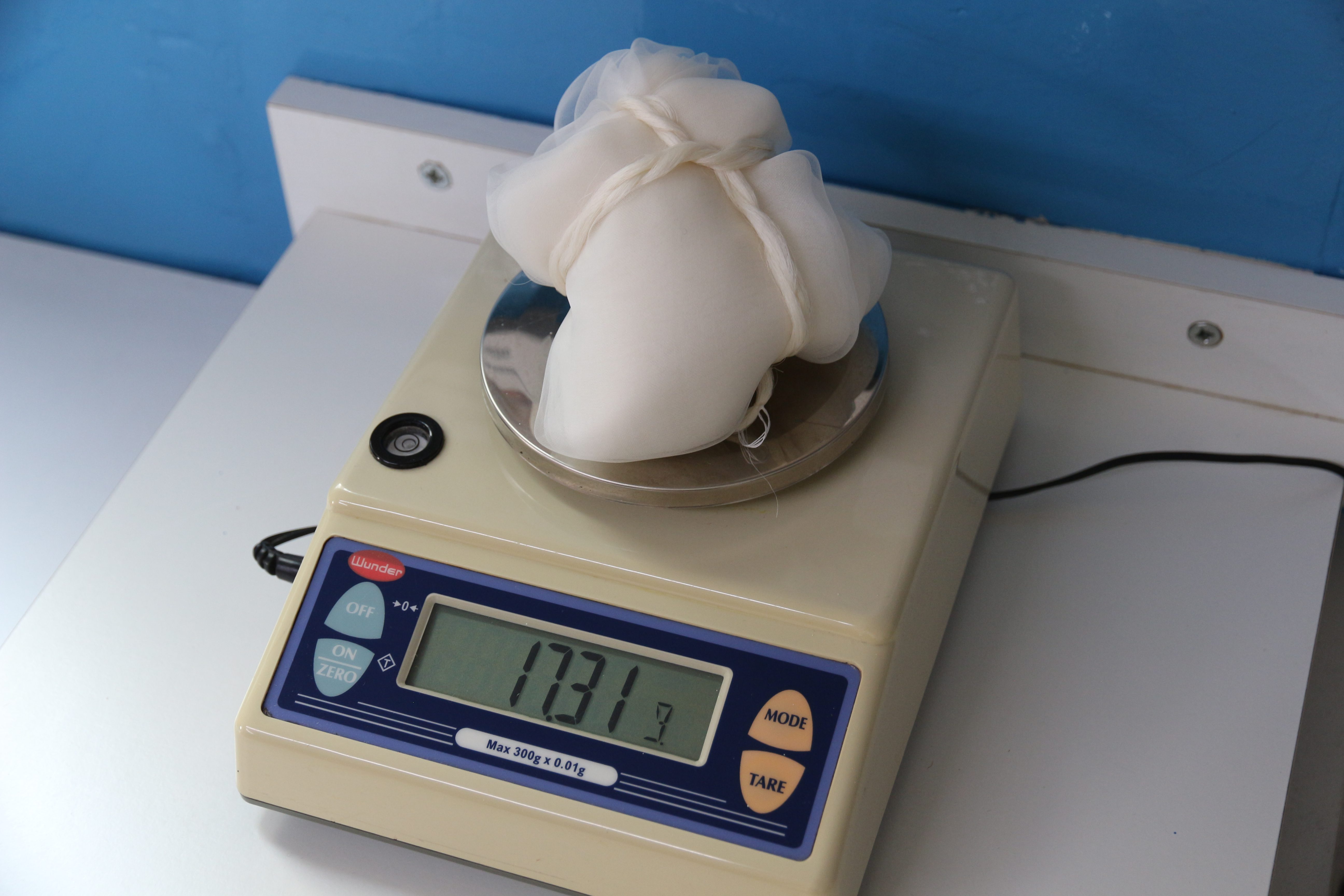 Silk fabric and threads are weighed on a precision balance in order to determine the correct amount of dyestuff. Tomedi Textilrestaurierung